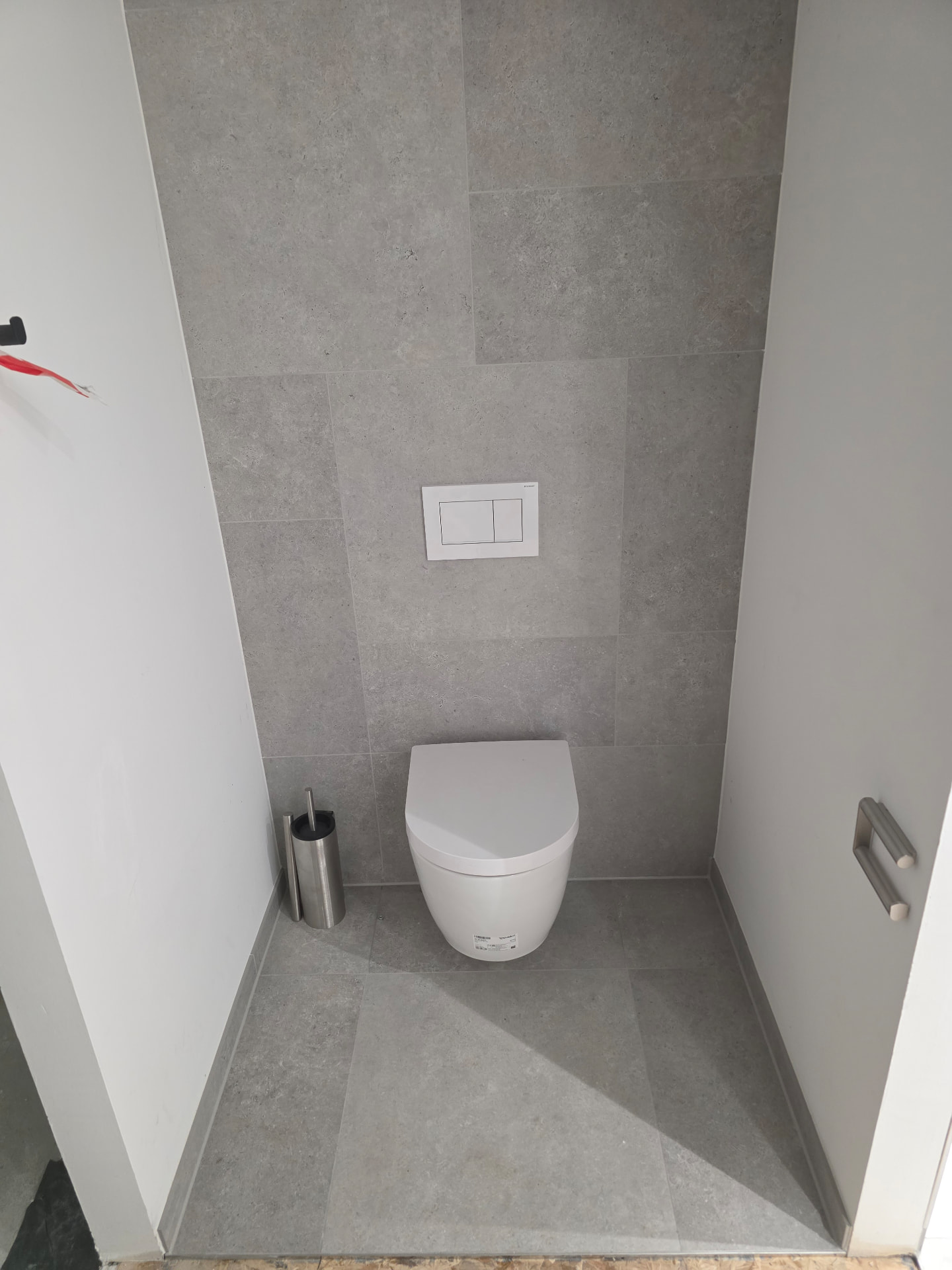 Wandhängendes WC im Muster-WC bei Rohde & Schwarz in München mit grauen Steinputz-Fliesen