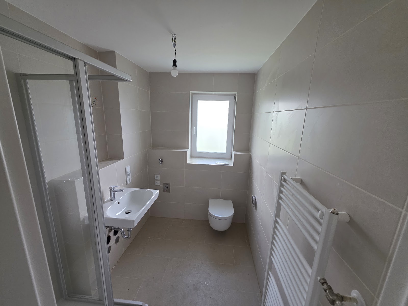 Badezimmer der Badsanierung in Welden mit Fensternische, Duschkabine und Handtuchheizkörper